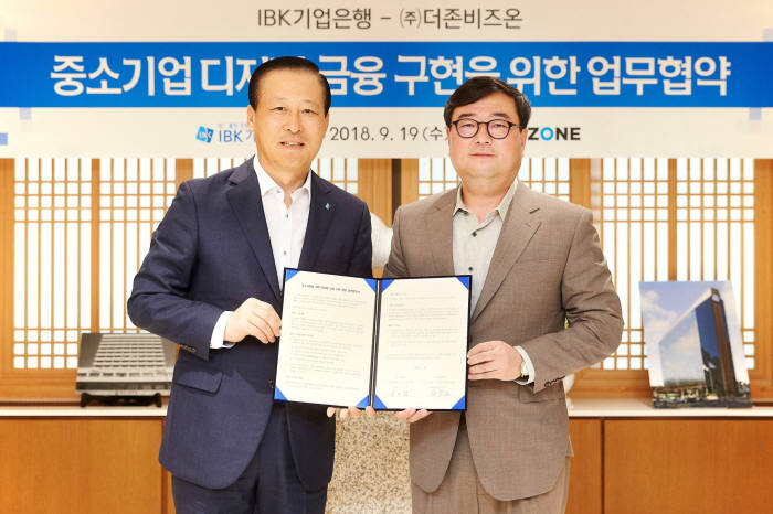 더존비즈온이 IBK기업은행과 19일 서울 을지로 기업은행 본점에서 사업제휴 양해각서(MOU)를 체결했다. 체결식에서 김도진 기업은행장(왼쪽)과 김용우 더존비즈온 대표가 사진촬영을 하고 있다. 더존비즈온 제공